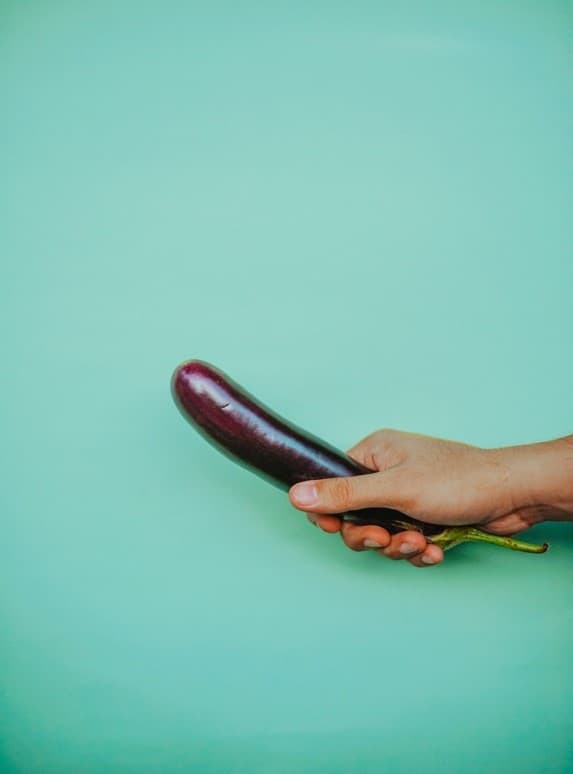 A Hand Holding the Top Part of a Penis-Shaped Aubergine
