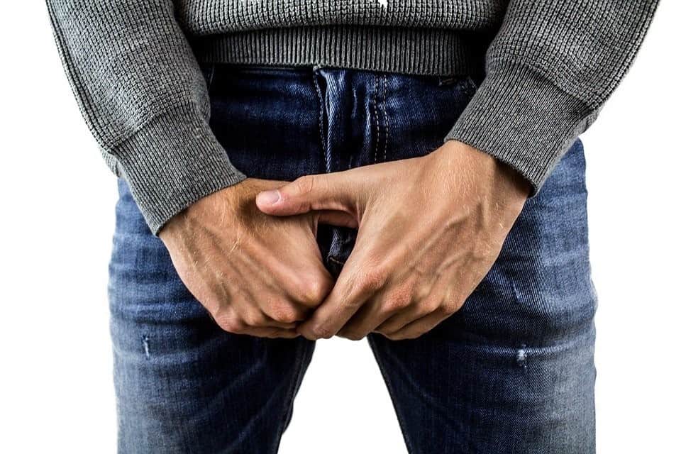 Waist-Down Image of a Faceless Man in Jeans Folding His Hands in Front of His Crotch Region