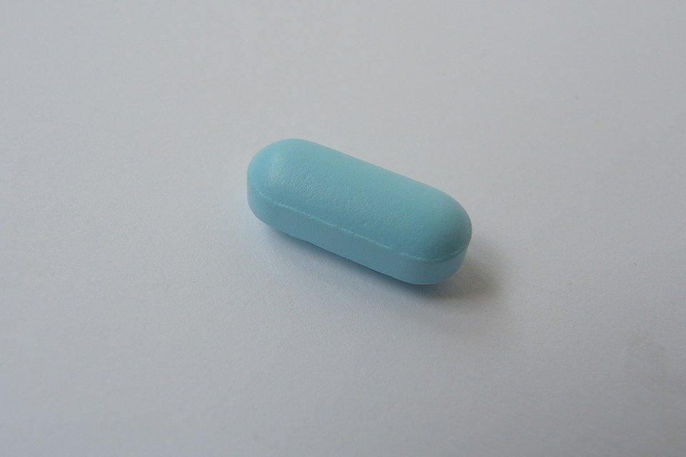 A Single Blue Tablet Lying on a Plain White Surface