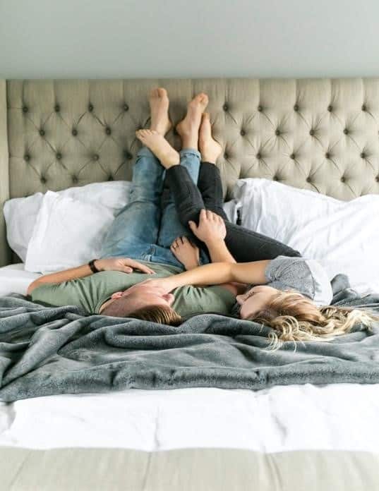 A Man and a Woman Cuddling While Lying Upside Down in Bed